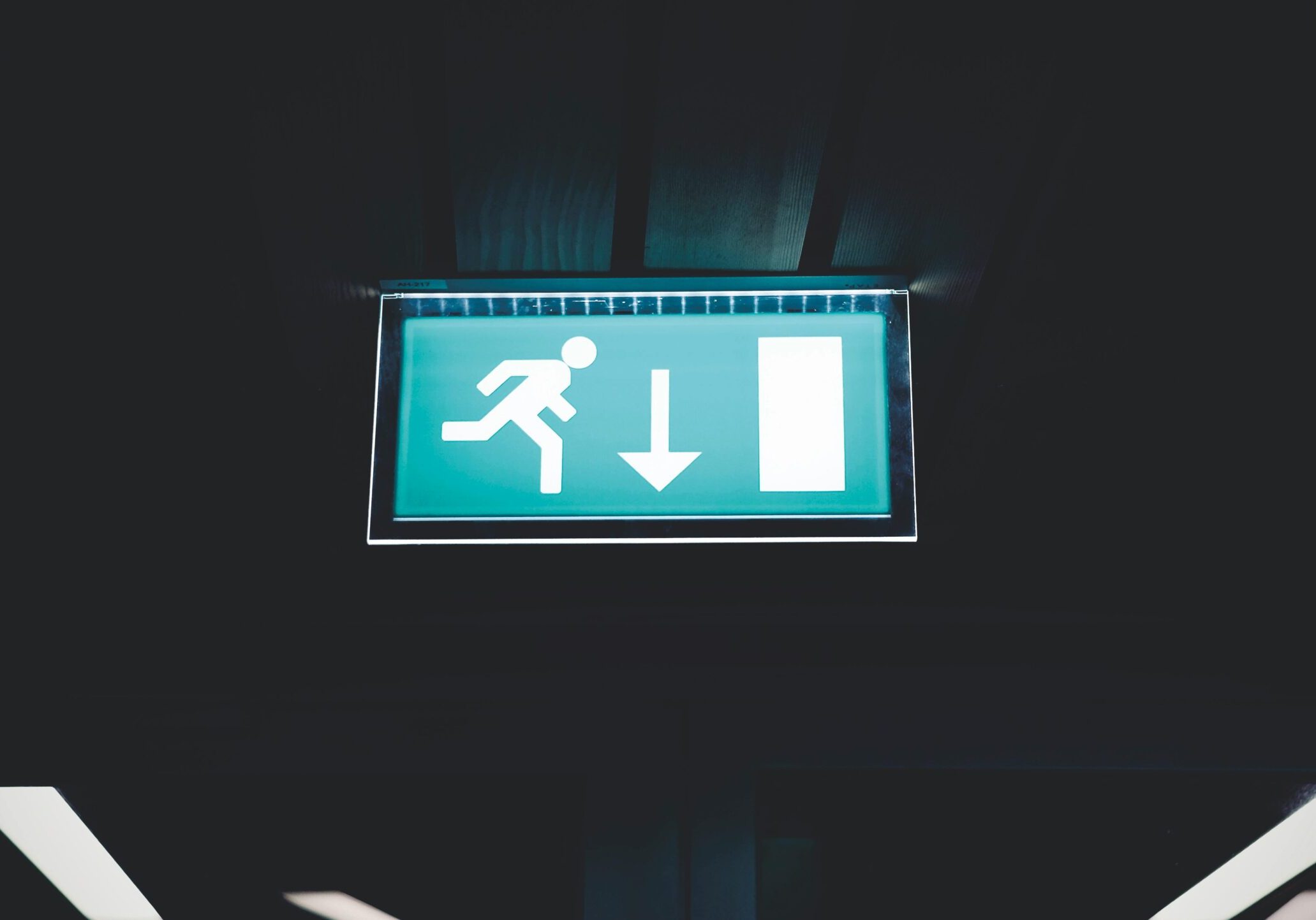 pexels-photo-845265-845265 Brightly lit emergency exit sign with arrow indicating direction, set against a dark backdrop.